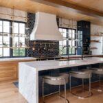 A kitchen with a large island and stools in it